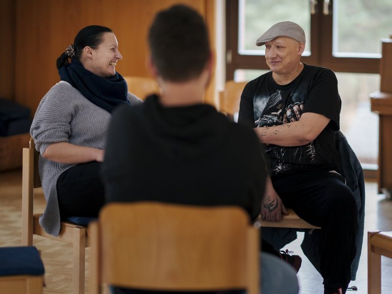 Drei Menschen in einer Sitzgruppe unterhalten sich angeregt.